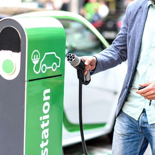 man charging electric car at charging point