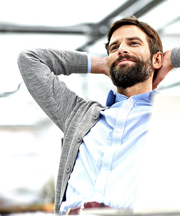 Hombre reclinado en su silla con sus manos detrás de la cabeza
