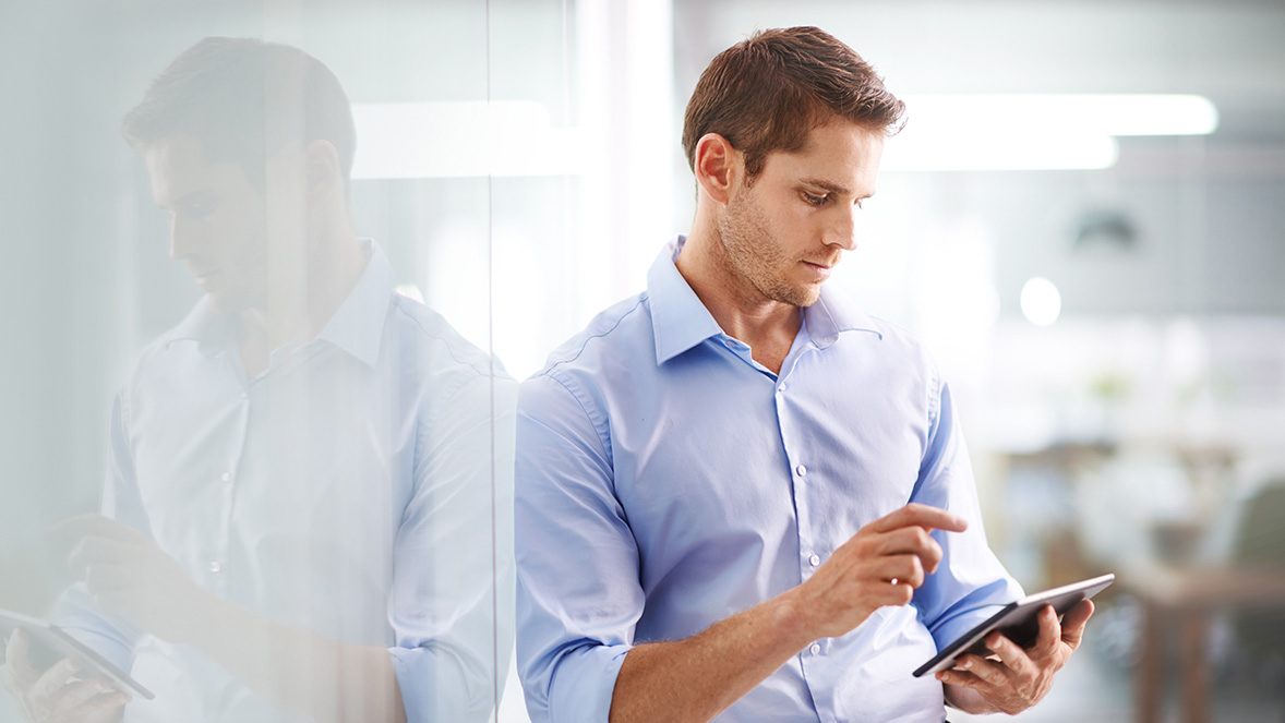 Hombre de negocios de pie utilizando una tablet en un espacio de trabajo Hombre de negocios de pie utilizando una tablet en un espacio de trabajo