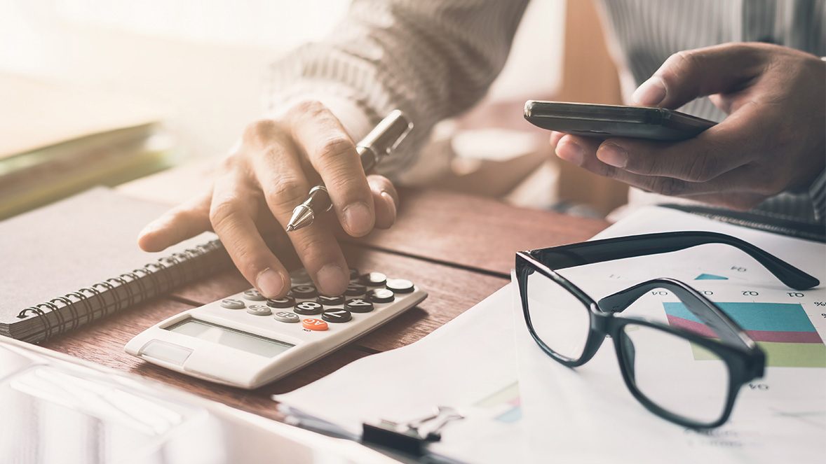 Primer plano de hombre trabajando con una calculadora y un teléfono Primer plano de hombre trabajando con una calculadora y un teléfono