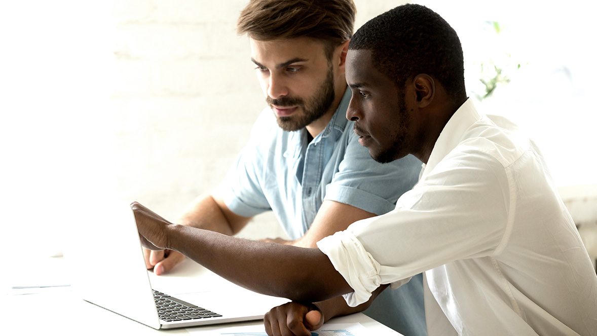 Dos compañeros de trabajo mirando la pantalla de un portátil Dos compañeros de trabajo mirando la pantalla de un portátil