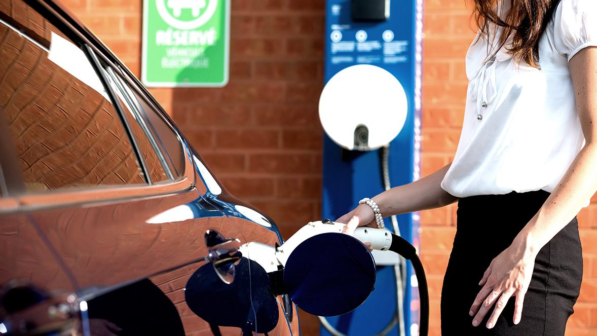 Mujer cargando un coche eléctrico Mujer cargando un coche eléctrico