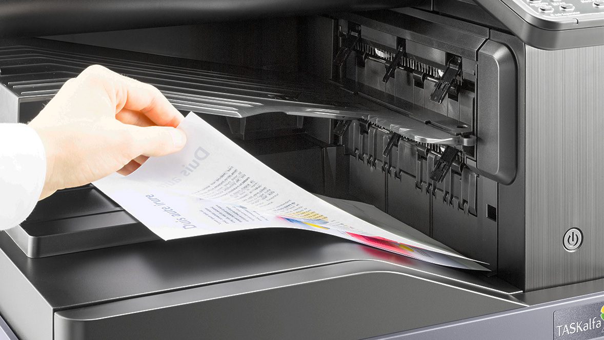 Primero plano de una mano cogiendo un documento de una multifuncional Primero plano de una mano cogiendo un documento de una multifuncional